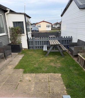 A backyard with a wooden fence, a picnic table, and outdoor furniture. - Chalet 91A South Shore Bridlington, Sleeps 4 (Bridlington)