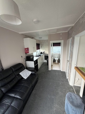 A compact living space with a sofa, kitchenette, and a bathroom. - Chalet 91A South Shore Bridlington, Sleeps 4 (Bridlington)