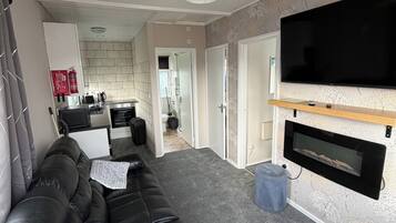 Sala de estar moderna com sofá de couro preto, televisão na parede e lareira.
