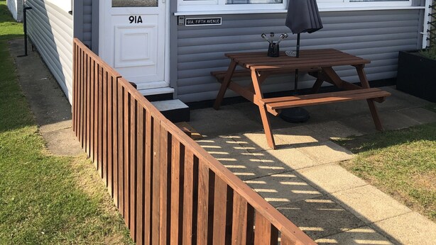 A single-story mobile home with a front door labeled "9A, Fifth Avenue," a wooden picnic table, and a small patio area. - Chalet 91A South Shore Bridlington (Bridlington)