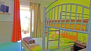 Ein Schlafzimmer mit Etagenbett aus Metall, einem Schreibtisch mit Lampe und einem Fenster mit Vorhängen.