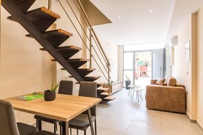 Un intérieur moderne avec une table à manger en bois, un canapé et un escalier.