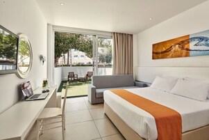 Habitación de hotel moderna con cama, escritorio, computadora portátil y vistas al exterior.