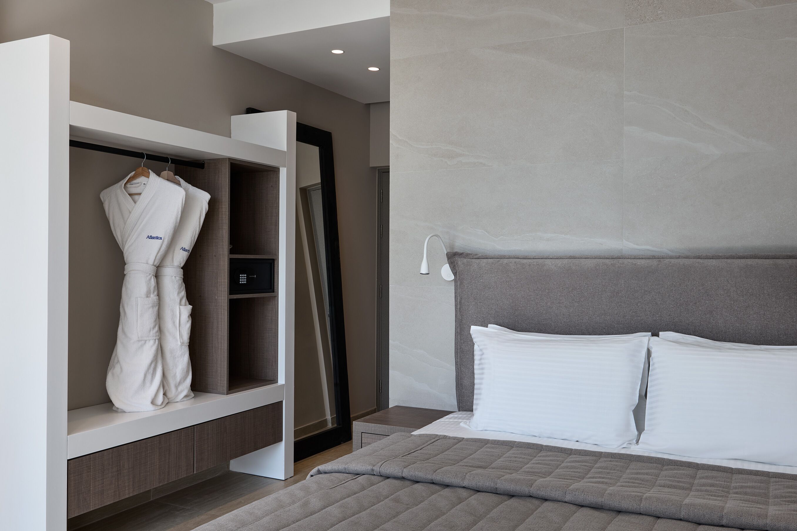Une chambre moderne avec un lit, un peignoir suspendu et une armoire intégrée.