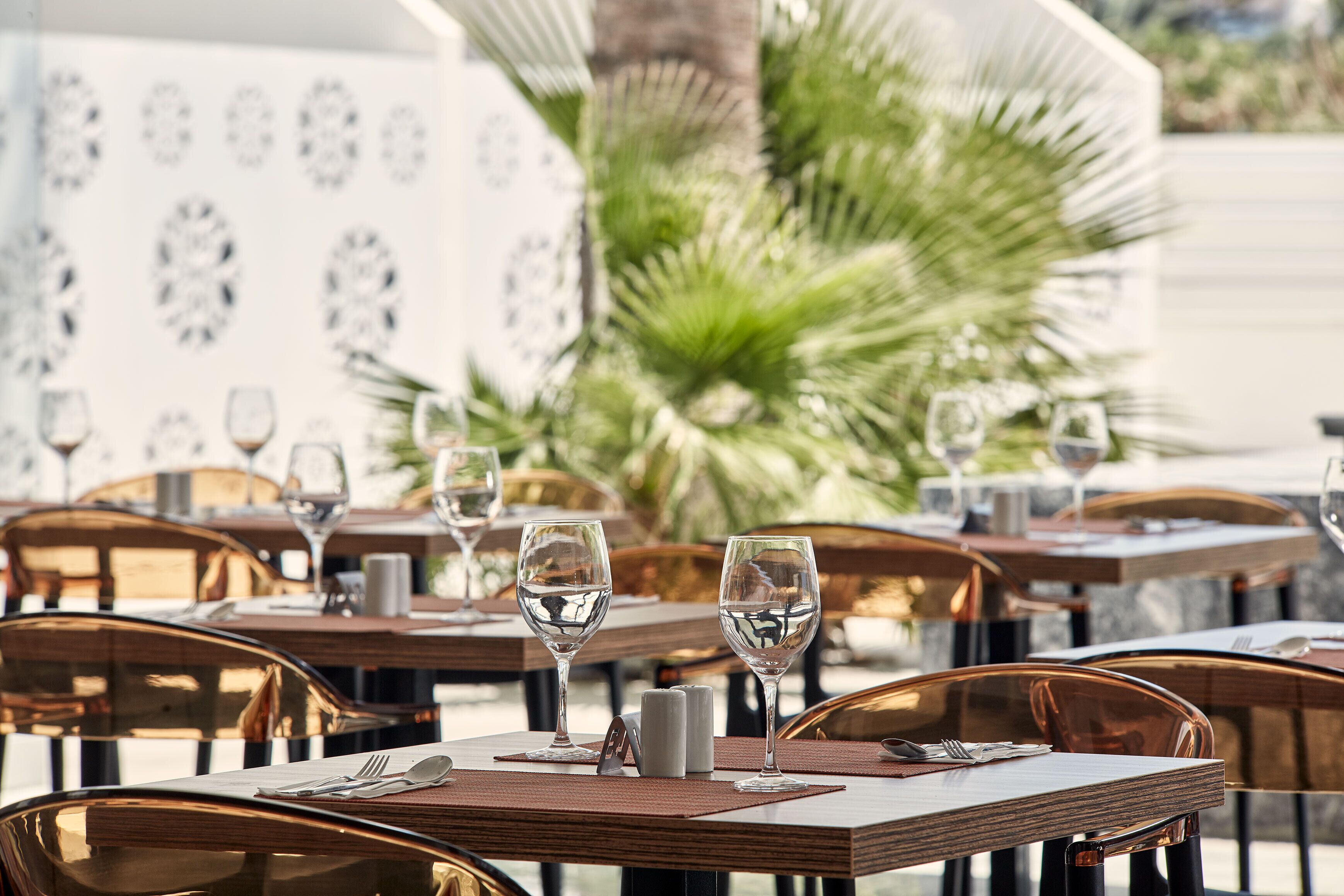 A restaurant setting with tables set for dining, featuring clear glassware and cutlery.