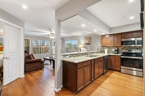 A modern kitchen with wooden cabinets, stainless steel appliances, and a large island. - 2 Bedroom, 2 Bath Walk-in Golf Condo featuring Whirlpool Tub & Sunroom with Course View (Branson)