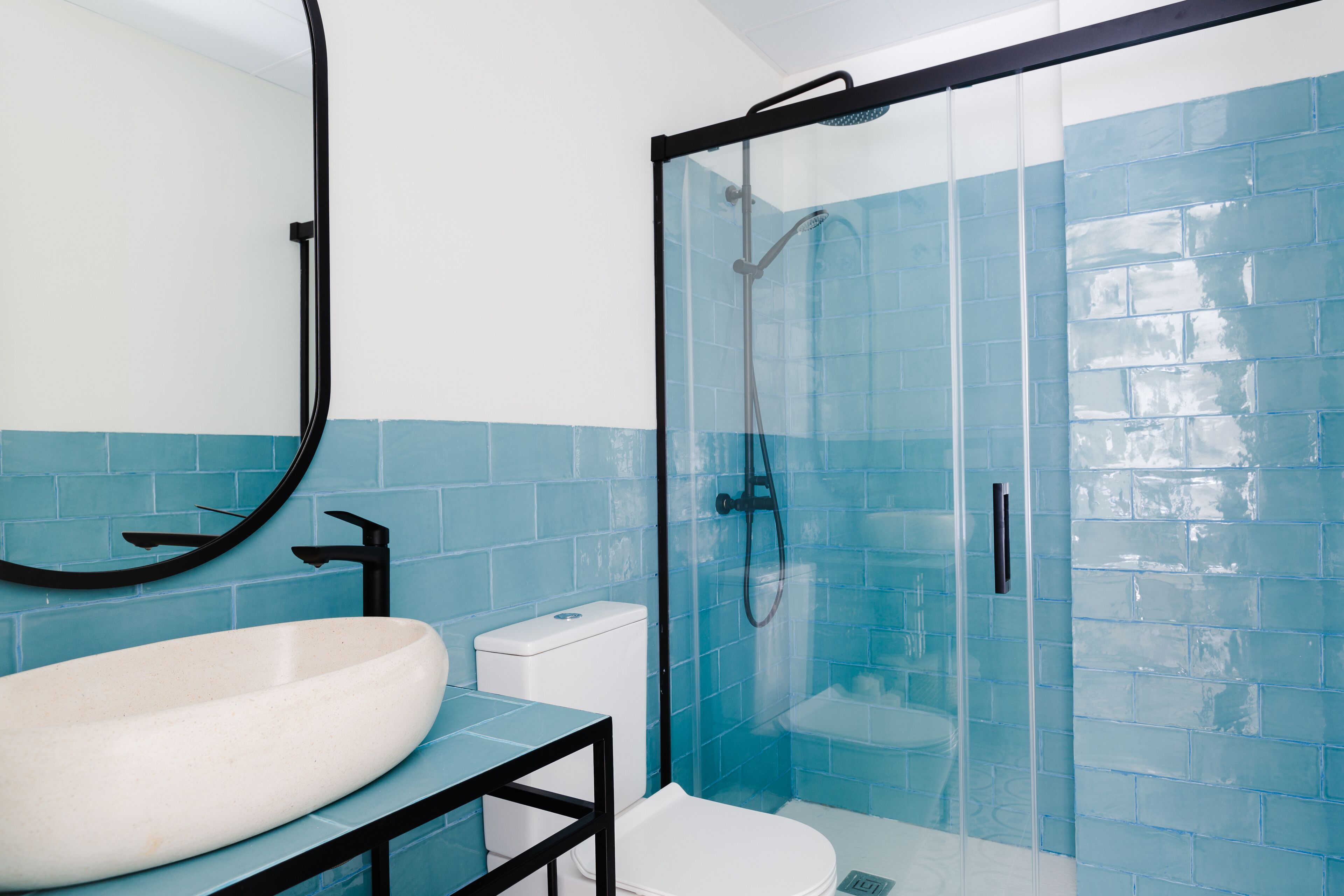 A bathroom with a large white sink, a toilet, and a glass-enclosed shower area.