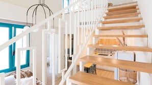 Un intérieur moderne avec un escalier en bois, des rampes blanches et un coin cuisine doté de plans de travail en bois.