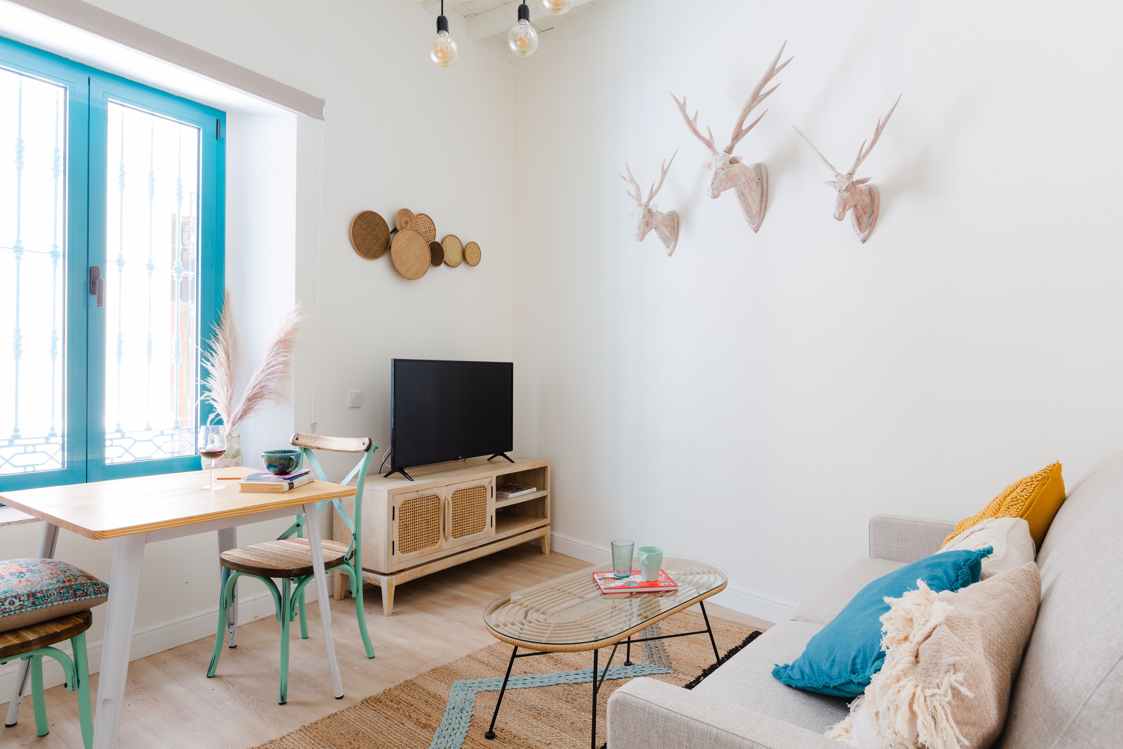 Uma sala de estar com televisão, sofá, mesa de centro e um espaço de jantar com cadeiras e mesa.