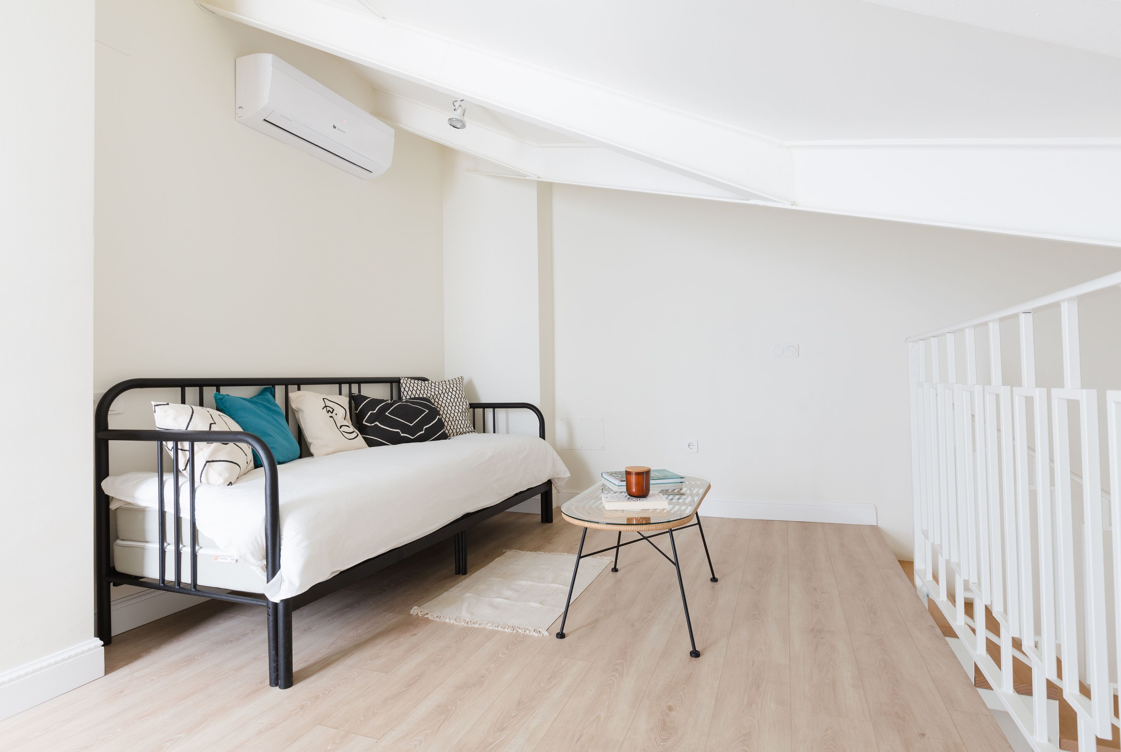 A bedroom with a bed, bedside table, and a white railing.