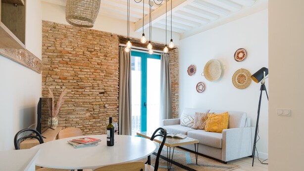 Un salon moderne avec un mur en pierre, un canapé blanc, une table à manger et une table basse.