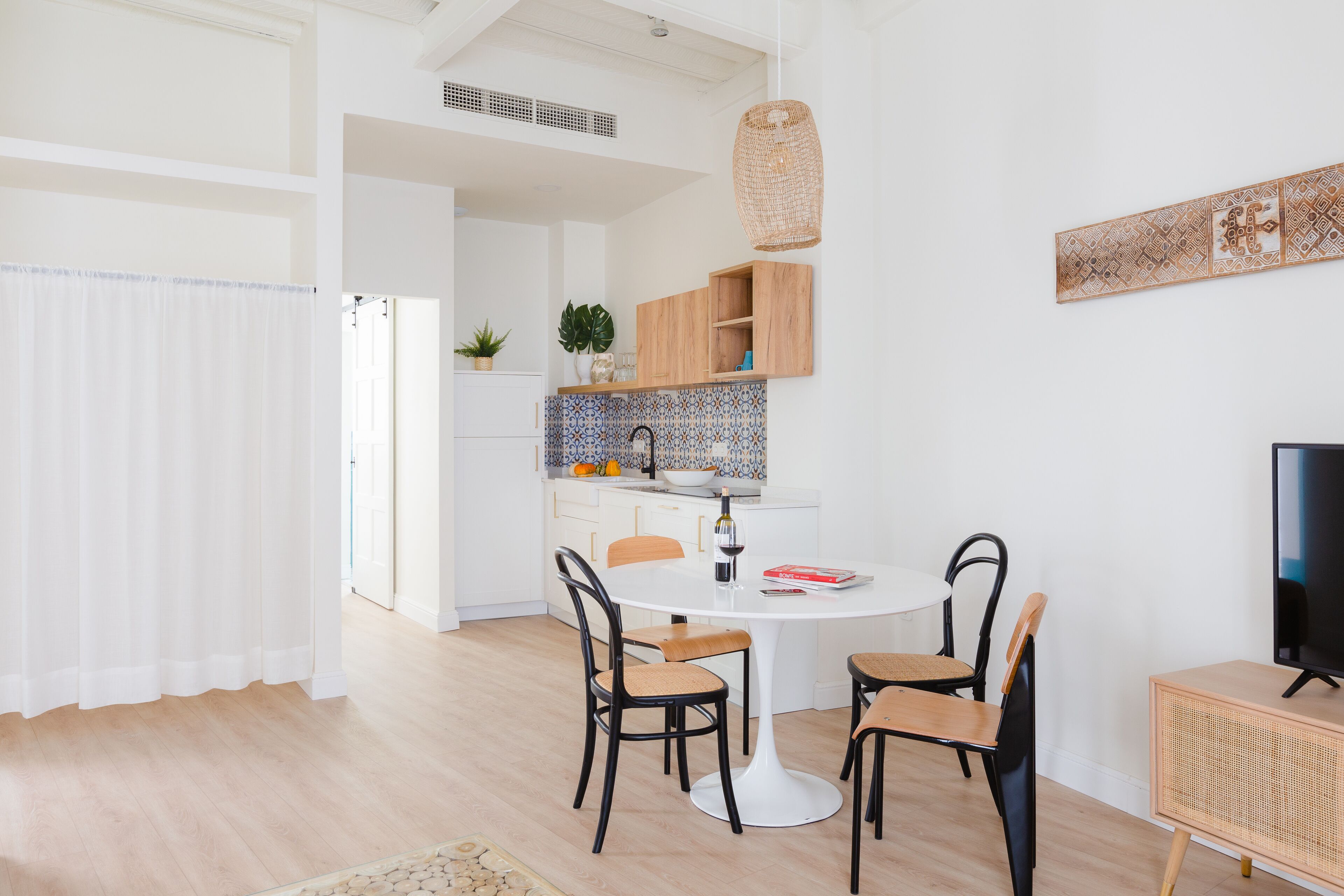 A modern kitchen with white cabinets, a round dining table, and black chairs.