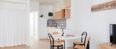 A modern kitchen with white cabinets, a round dining table, and black chairs.