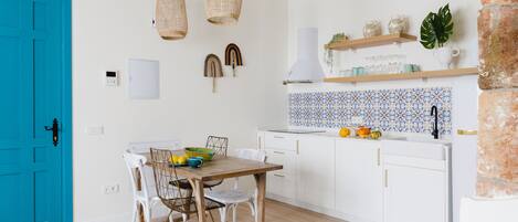 A kitchen with white cabinets, a blue door, and a tiled backsplash.