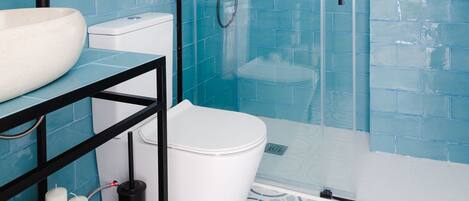 A modern bathroom with a glass-enclosed shower, a white toilet, and a sink with a black countertop.
