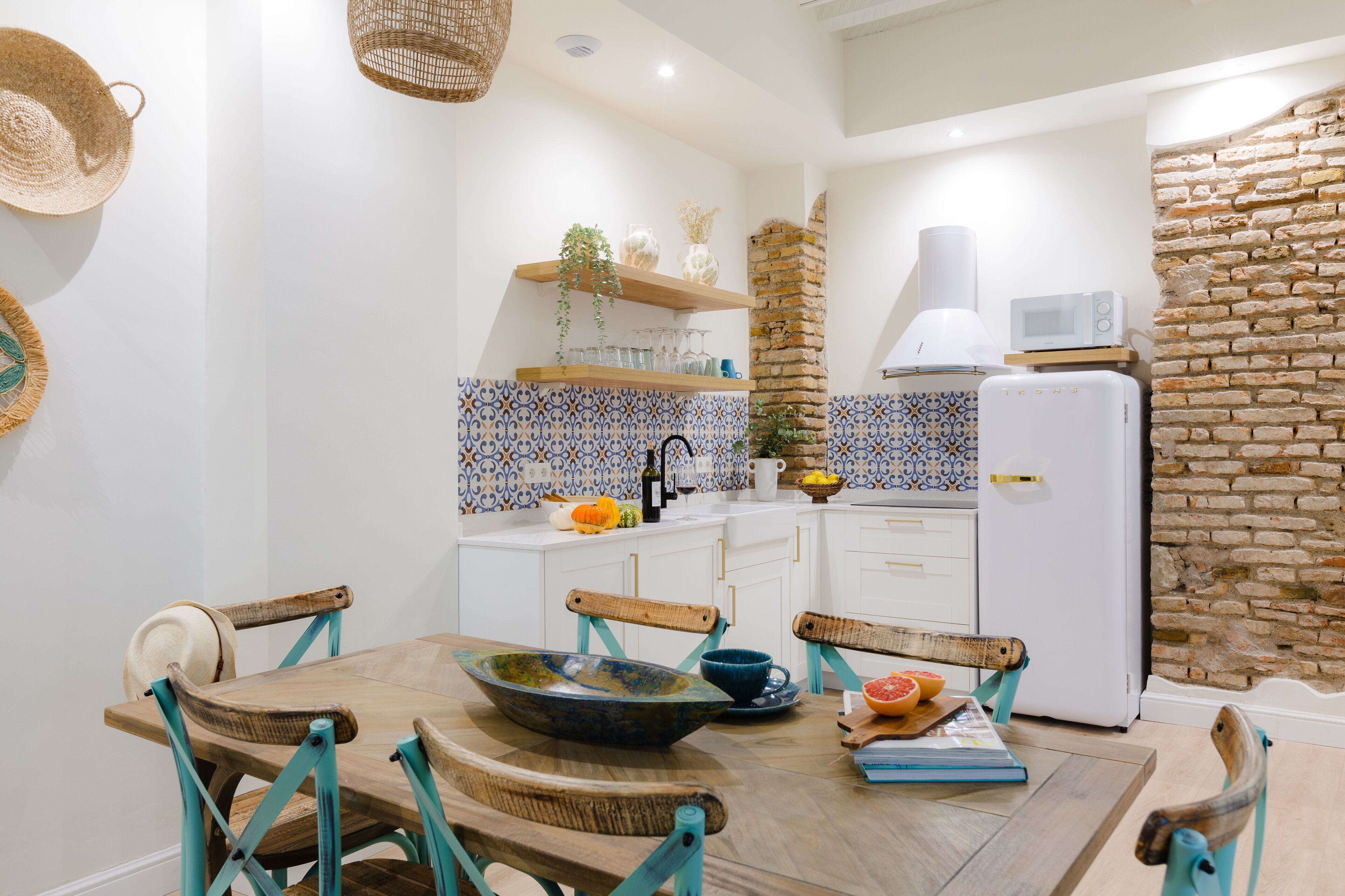 A compact kitchen with white cabinets, a microwave, and a brick wall.