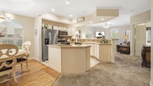 Una cocina amplia con una isla central, electrodomésticos integrados y una zona de comedor con mesa y sillas de madera.