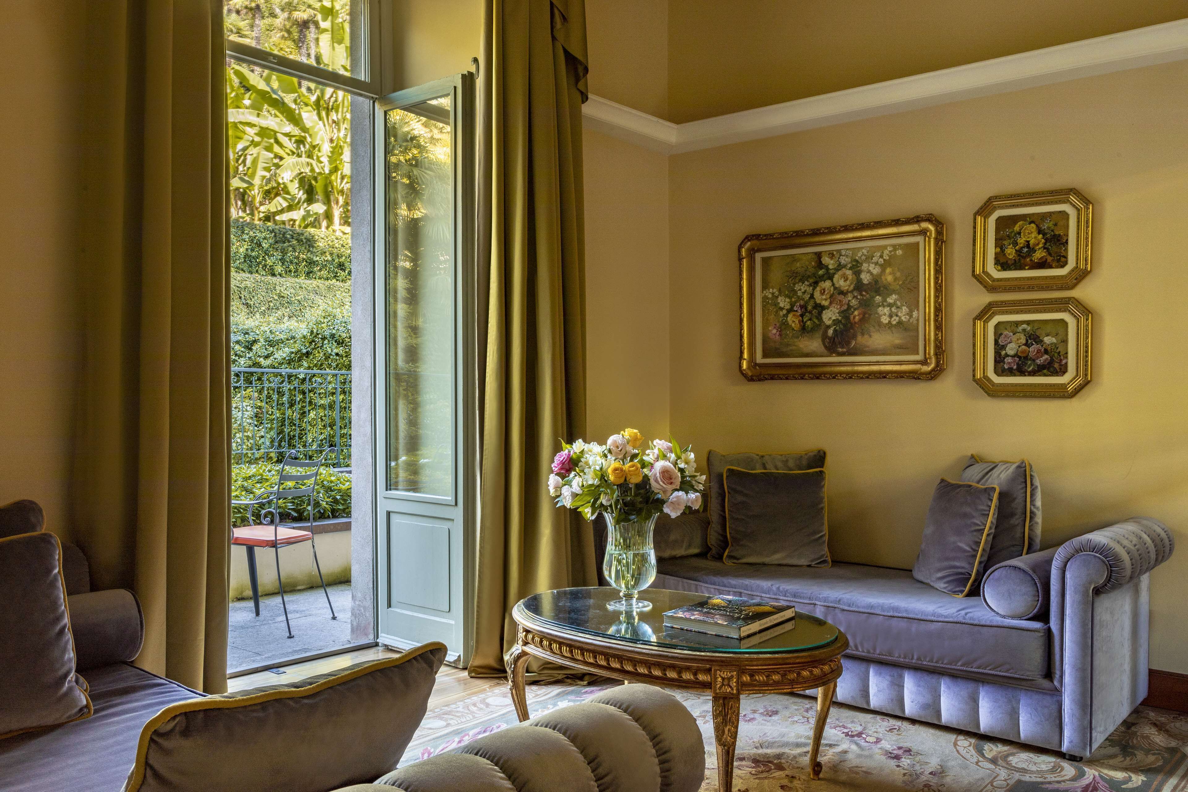 Een woonkamer met een bank, fauteuils, een salontafel en een raam met gordijnen.