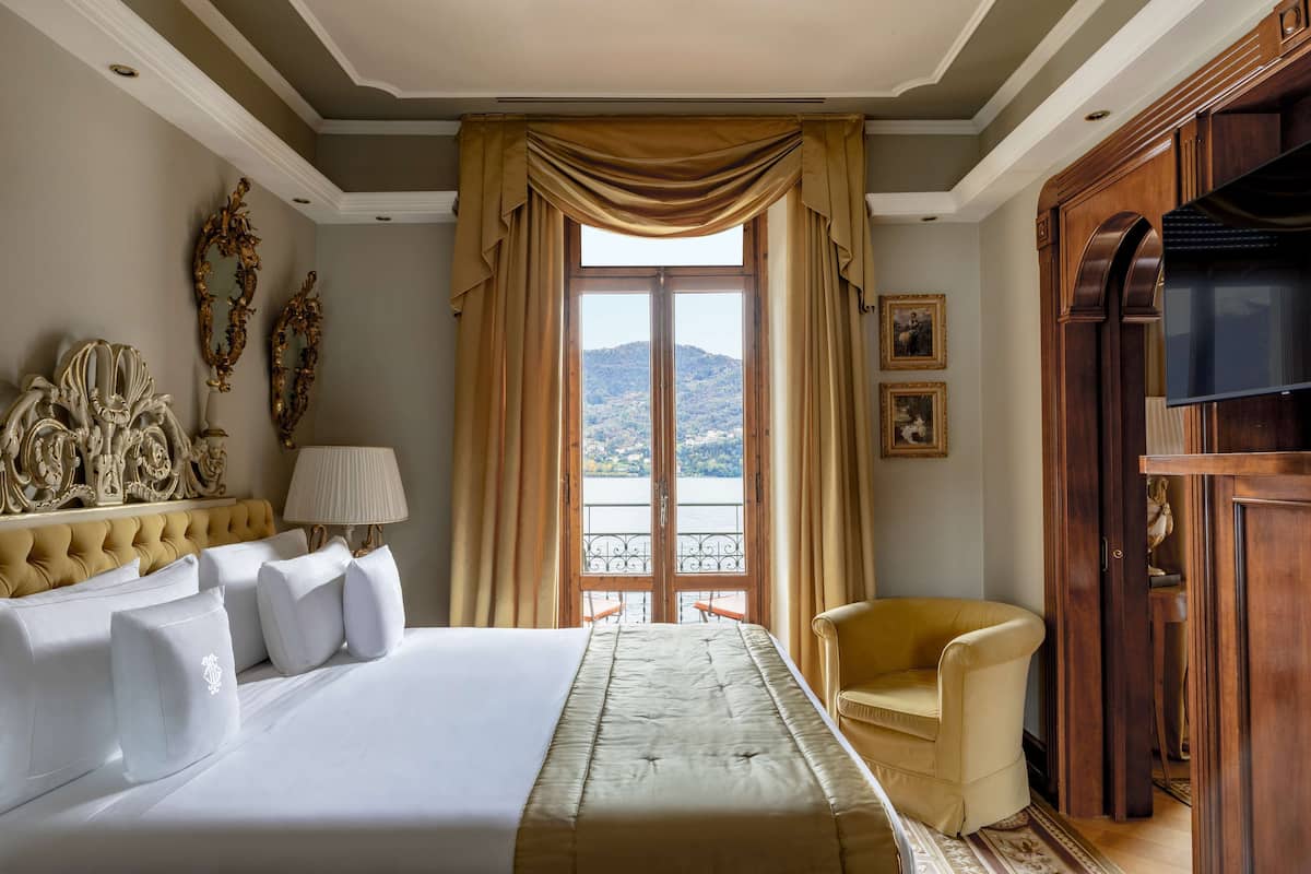 A hotel room with a large bed, a chair, a TV, and a view of the outdoors.