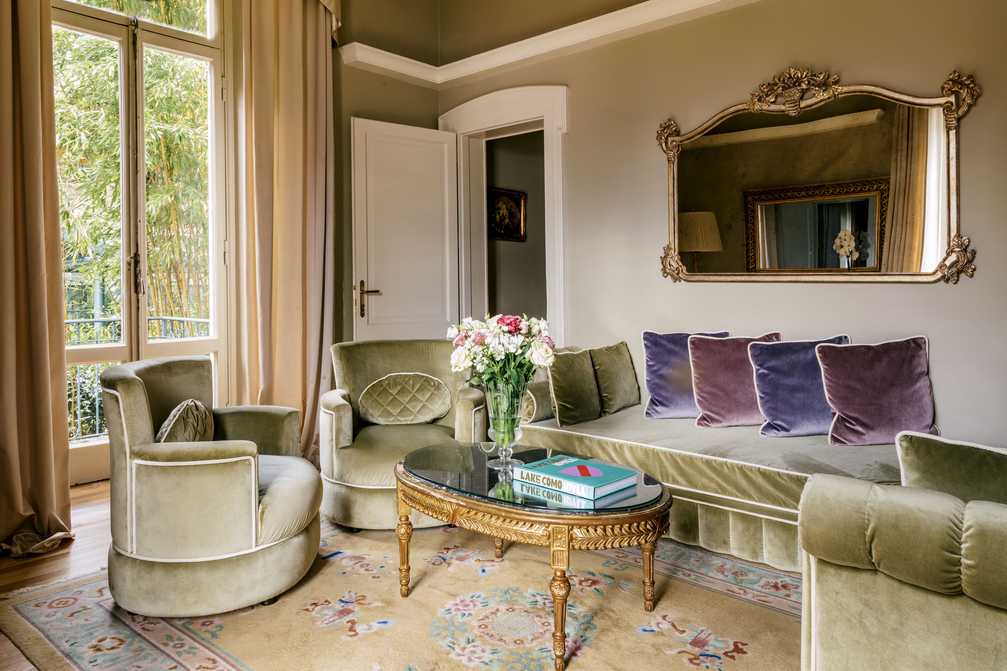 A living room with a sofa, armchair, and a coffee table with a book and vase.
