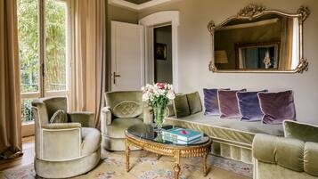 A living room with a sofa, armchair, and a coffee table with a book and vase.