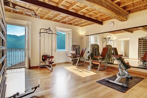 A gym with exercise equipment, large windows, and a wooden ceiling.
