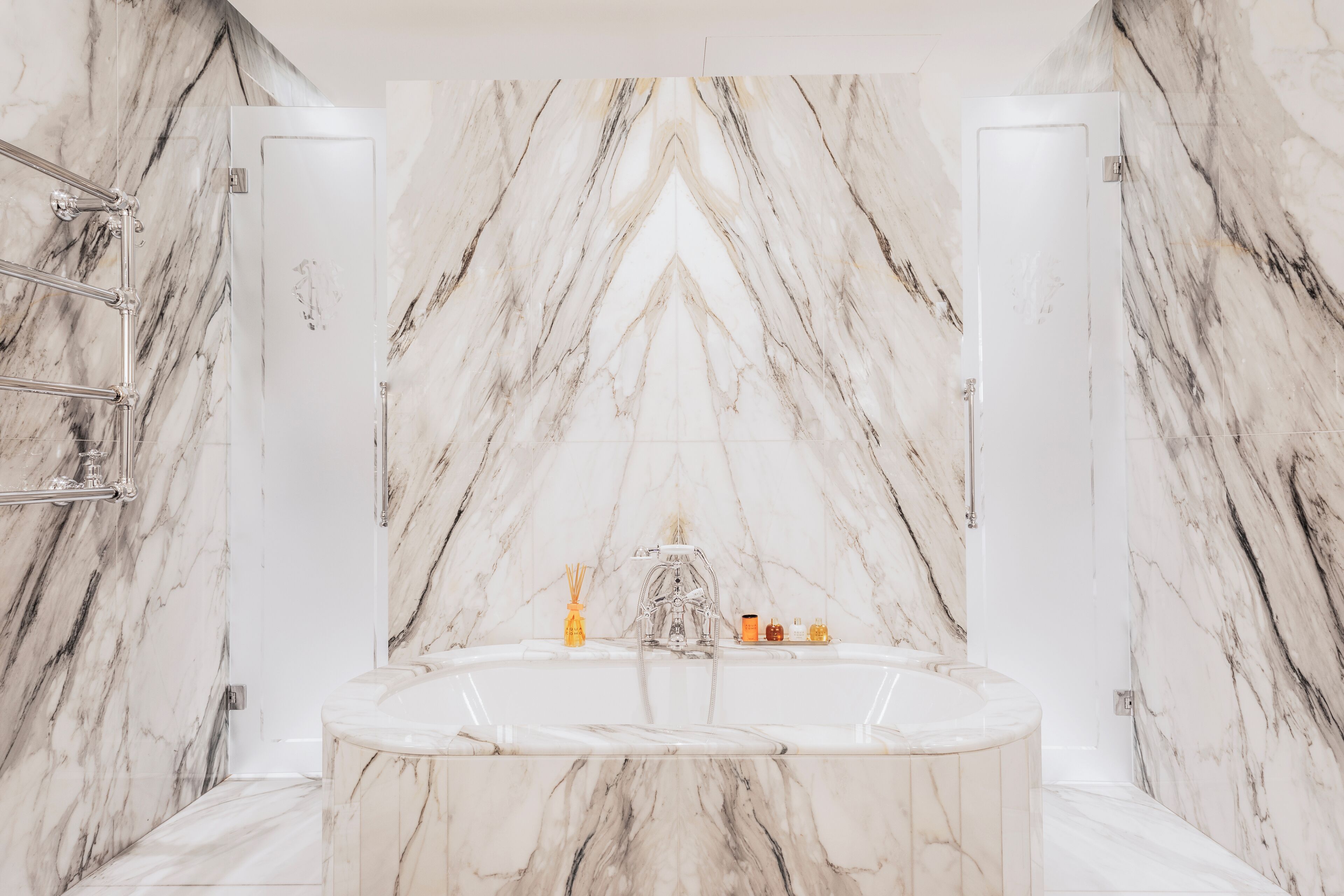 Ein Badezimmer mit Marmorwand, einer Badewanne und einer Duschkabine.