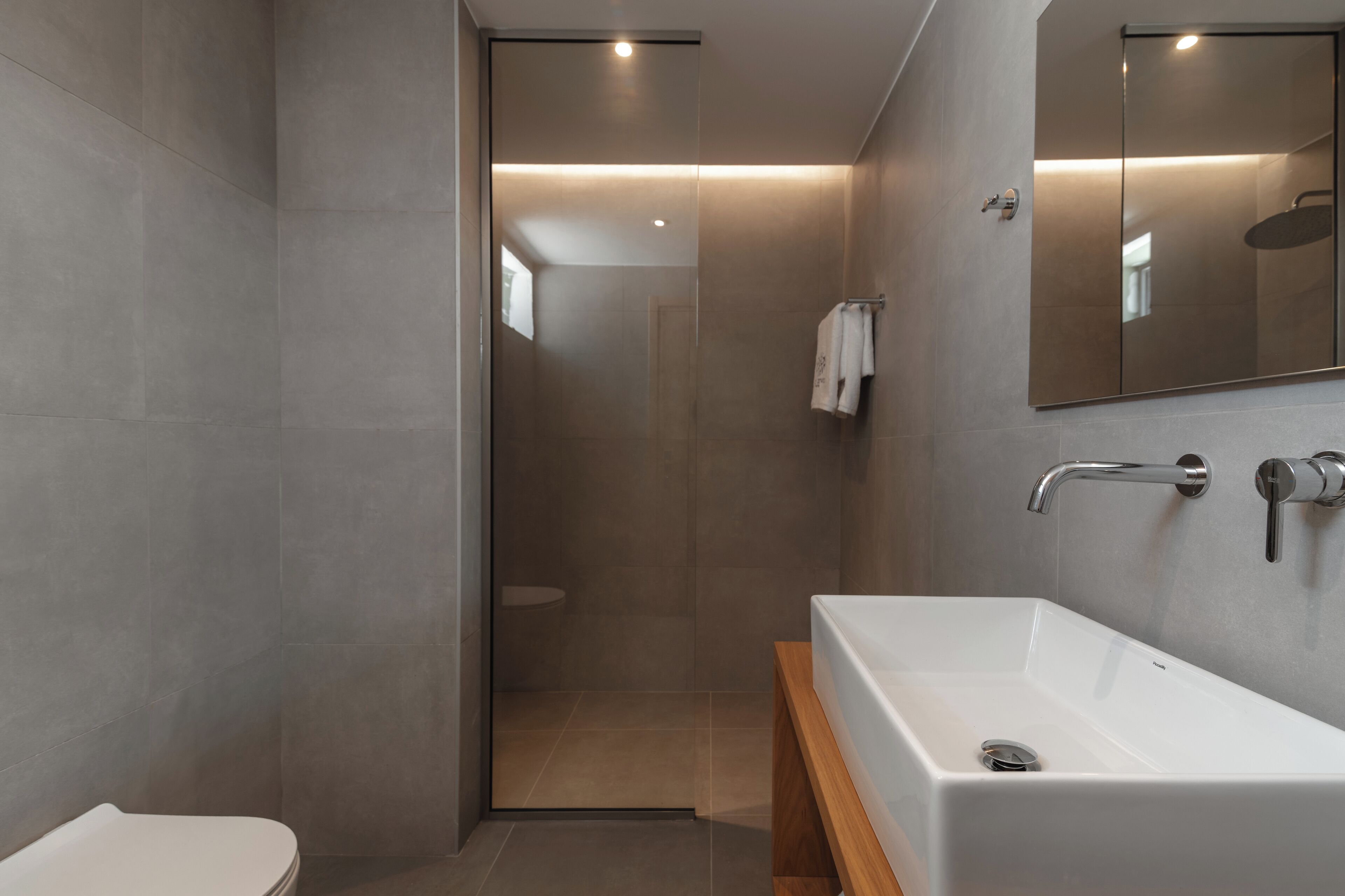 A modern bathroom with a large white bathtub, a shower area, and a toilet.