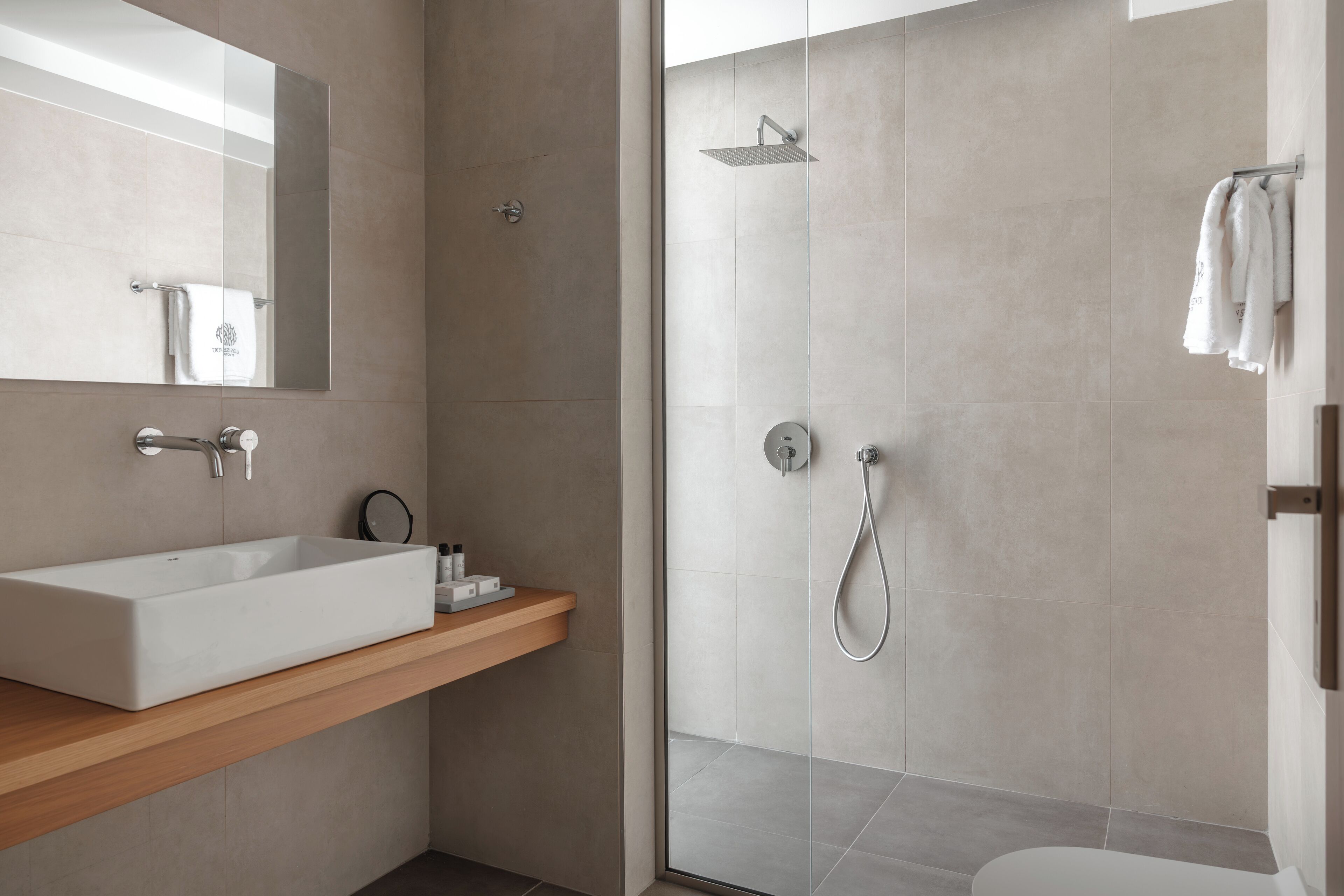 Un baño moderno con un lavamanos rectangular grande, un cabezal de ducha de mano y una ducha con mampara de vidrio.