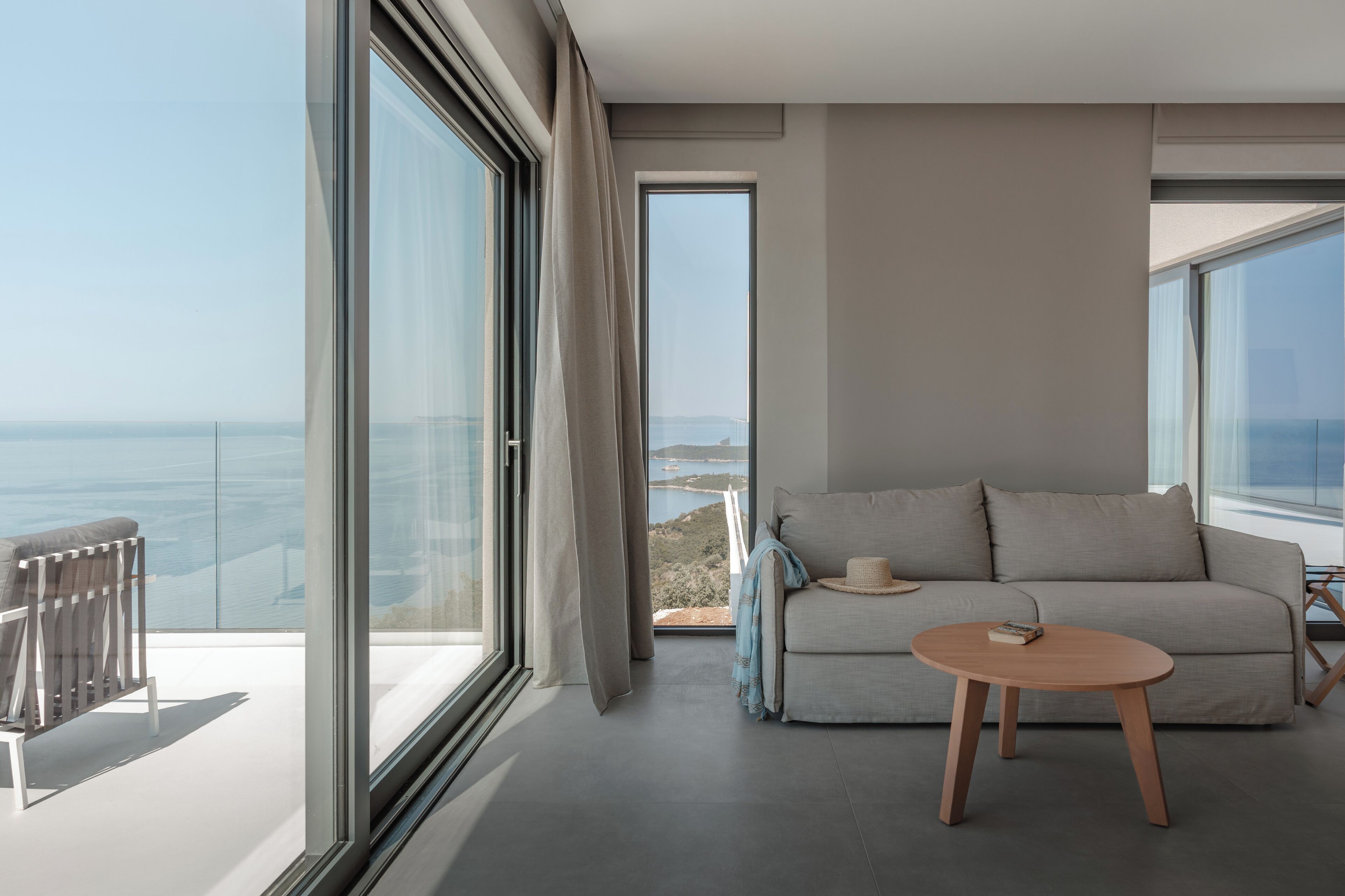 Una sala de estar moderna con un ventanal grande, un sofá, una mesita redonda y vista al mar.