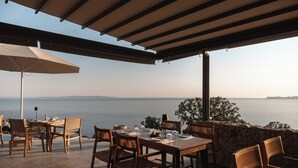An outdoor dining area with a table set for four, overlooking a body of water. - Alon Sevou Boutique Hotel (Igoumenitsa)