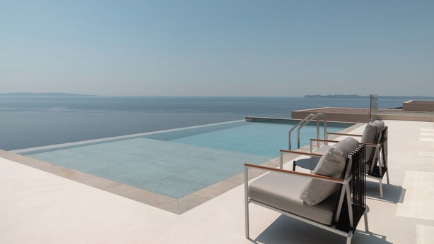 A rooftop infinity pool with a clear view of the ocean, accompanied by two lounge chairs and a small table. - Alon Sevou Boutique Hotel (Igoumenitsa)