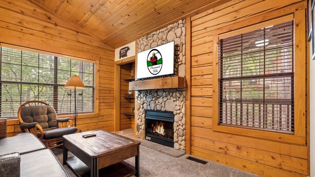 Ein gemütliches Blockhaus-Interieur mit Kamin aus Stein, Holzwänden und einer bequemen Sitzecke.