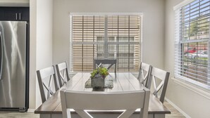 Un comedor con mesa, sillas y una ventana con persianas.