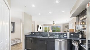 Una cocina moderna con armarios oscuros, electrodomésticos de acero inoxidable y una isla grande con pileta.