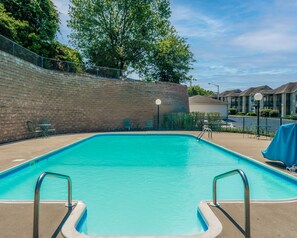 Une piscine rectangulaire avec des garde-corps en métal, entourée d’un mur de briques et d’une clôture.