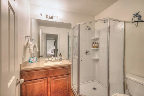A bathroom with a wooden vanity, a sink, a mirror, and a glass-enclosed shower.