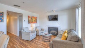 Ein Wohnzimmer mit Kamin, zwei Sesseln, einer Couch und einem Couchtisch.