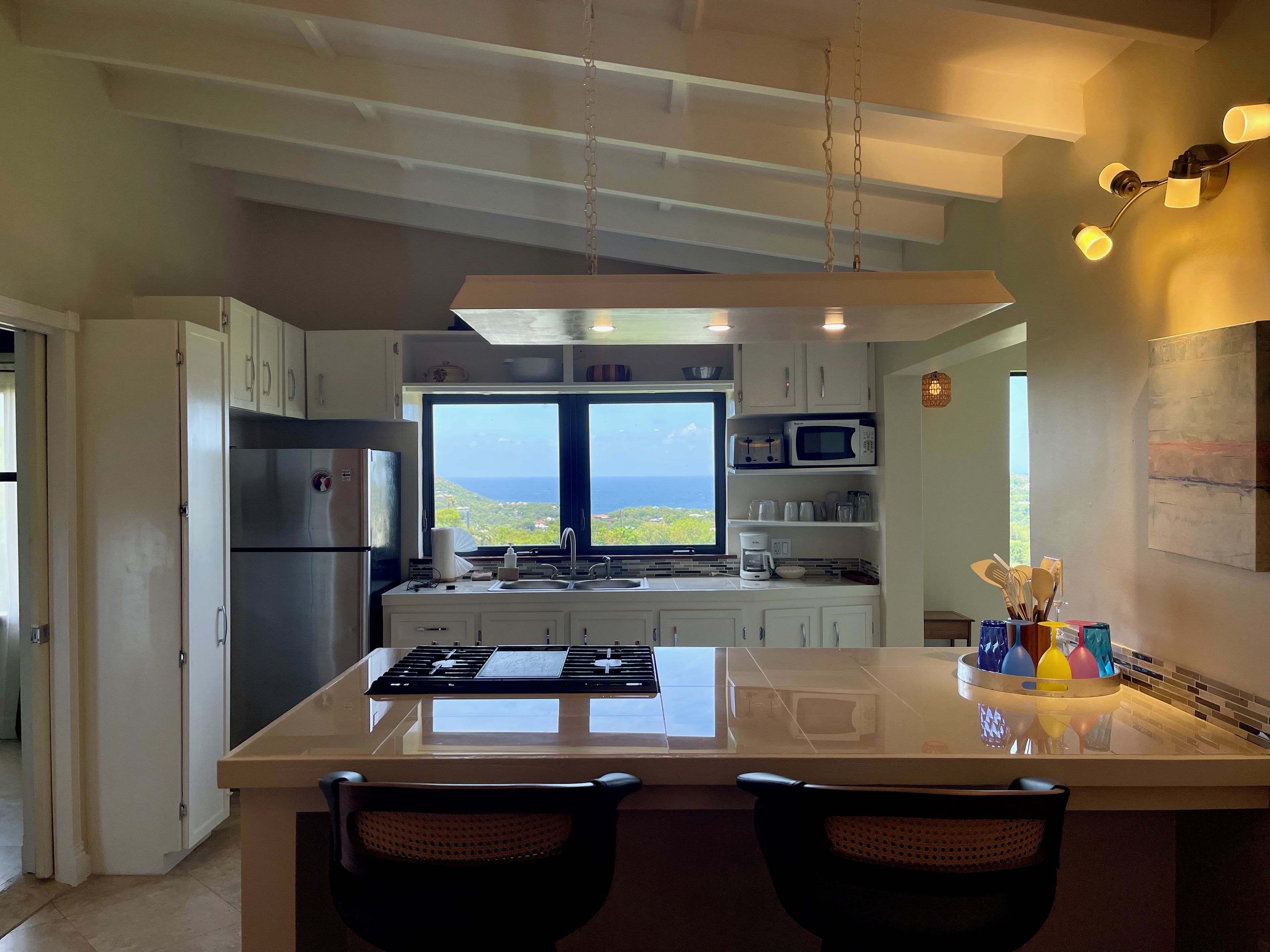 A modern kitchen with a large island, stainless steel appliances, and a view of the ocean.