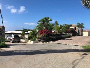 A residential driveway with a parked SUV, a stone wall, and a house with a tiled roof.