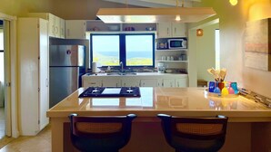 A modern kitchen with a large island, stainless steel appliances, and a view of the ocean. -  2-bedroom-ocean & St Croix views-5 minutes to Cruz Bay (Cruz Bay)