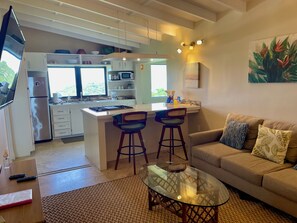 A modern kitchen with a central island, bar stools, a glass coffee table, and a sofa with patterned cushions. - Ocean view 2 bedroom minutes to Cruz Bay (Cruz Bay)