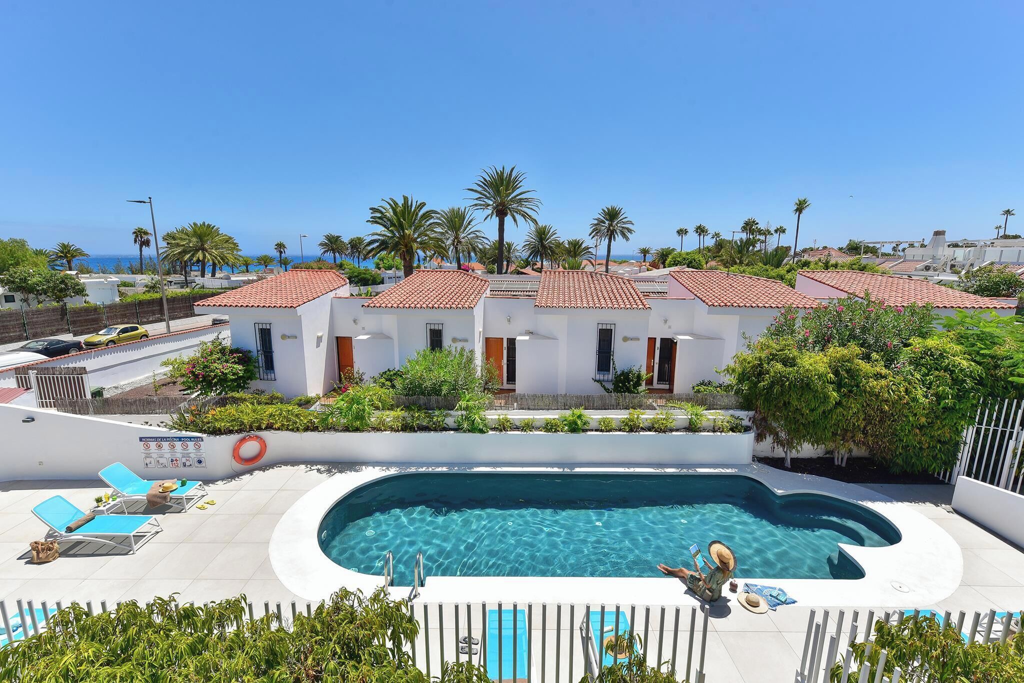 A pool area with lounge chairs, a swimming pool, and a view of the sea.