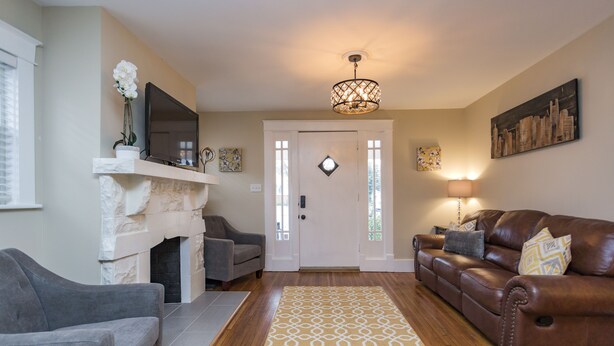 A living room with a fireplace, a sofa, a couch, a patterned rug, and a chandelier. - Red Nashville Beauty 3BD/2BT - 12Min from Downtown (Nashville)