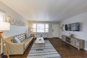 Ein Wohnzimmer mit einer Couch, einem Couchtisch und einem an der Wand befestigten Fernseher.