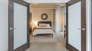Une chambre à coucher comprenant un lit, une table de chevet, une lampe et un miroir fixé au mur.