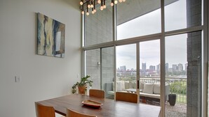 A modern dining area with a wooden table, chairs, and a city view through large windows. - Luxe Downtown Penthouse with City Skyline Views (Nashville)