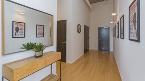 A hallway with a wooden bench, a potted plant, framed pictures on the walls, and a door at the end. - Luxe Downtown Penthouse with City Skyline Views (Nashville)