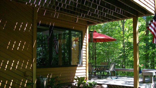 A covered outdoor area with a table and chairs, a trash can, and a red umbrella. - Clean and Cozy, Beautiful, well kept Trout Creek Condominium Unit 79 Building 11 (Harbor Springs)