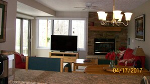 A living room with a television, fireplace, and dining area. - Clean and Cozy, Beautiful, well kept Trout Creek Condominium Unit 79 Building 11 (Harbor Springs)